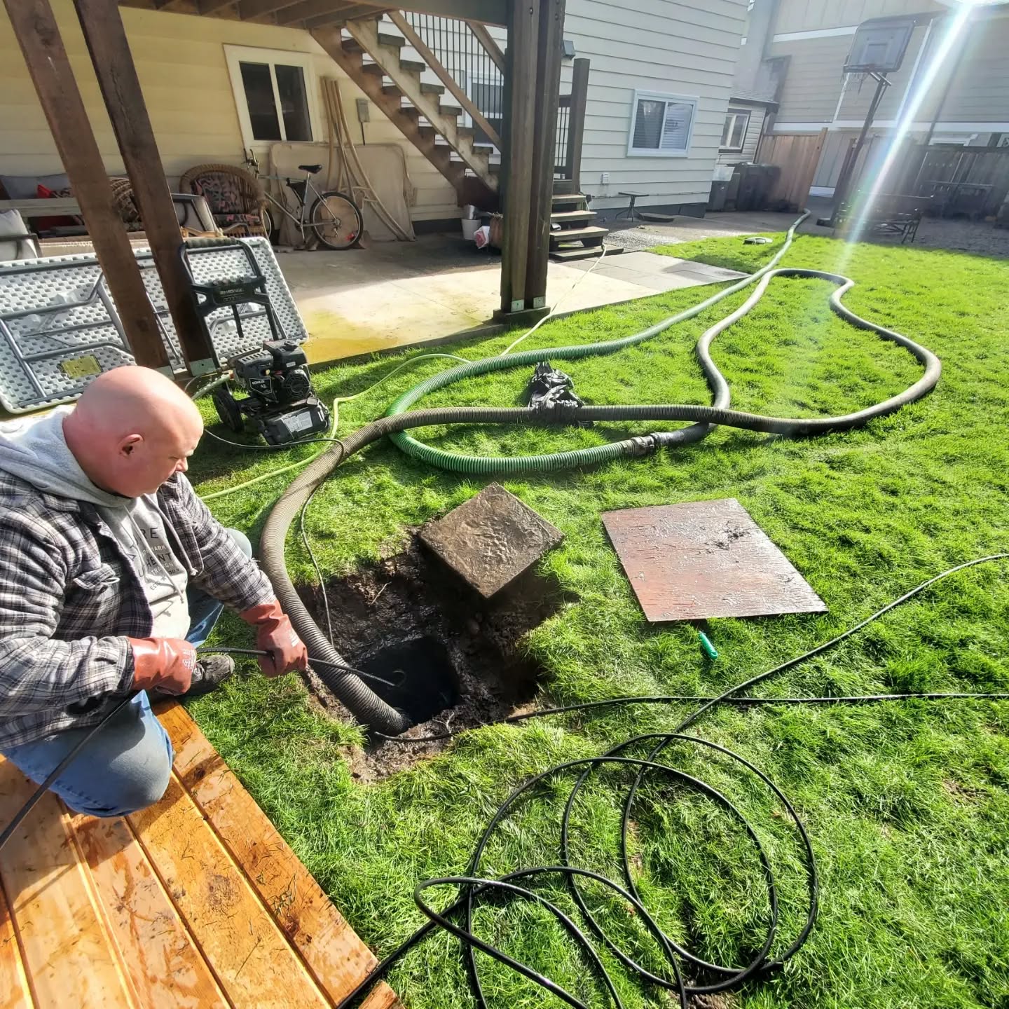 Clearset hydrojetting service being performed by a bald man in a grassy residential backyard.