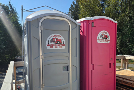 Two porta-potties, rented from Clearset VAC Truck Services in Port Coquitlam, set up in an outside event on grass.