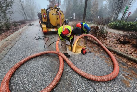 Two employees of Clearset VAC Truck Services, unclogging a storm drain during a foggy Vancouver day